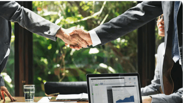 Two fractional executives who are businessmen shaking hands in office.